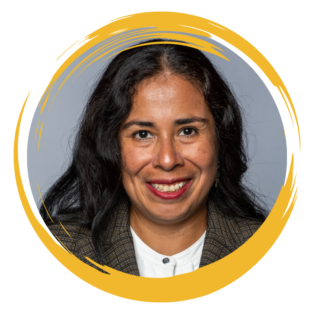 Image of Board member and faculty fellow, Irma. She is wearing a textured-brown blazer and a white dress shirt.
