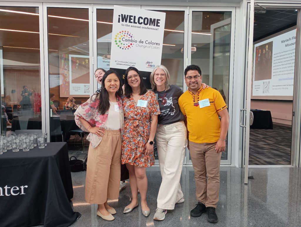 Group of 5 people in front of a WELCOME sign for the conference